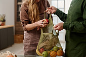 Woman putting apple into shopping bag