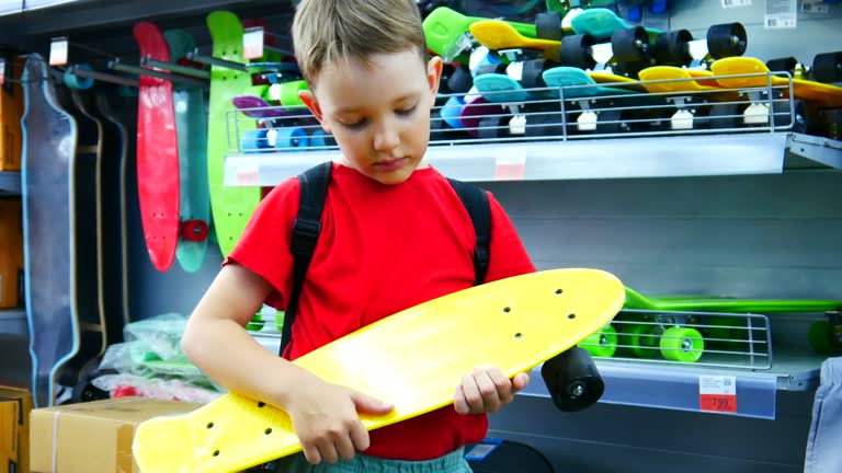 A cute boy holding a skateboard in a skate shop