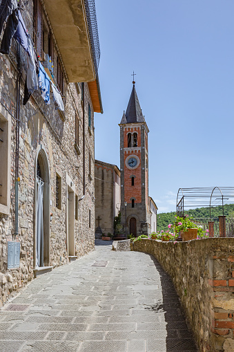 Walking narrow stone streets of old small mountain town.View of ancient Santa Maria Assunta church. Ambra, Bucine, Arezzo, Tuscany, Italy