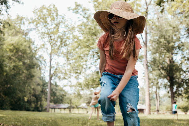 Little girl wearing sunhat runs and plays outdoors on summer day