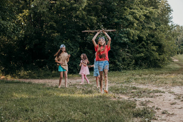 Group of children play in the dirt while exploring nature at summer camp