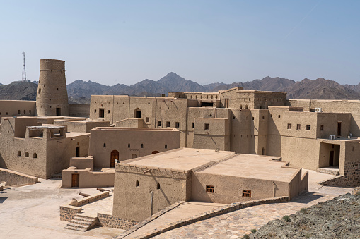 Bahla Fort from above, in distance Nizwa town against mountain range. Oman