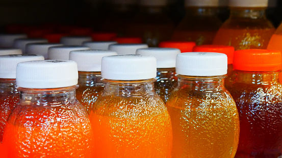 Many bottles of different juices on a store shelf close-up