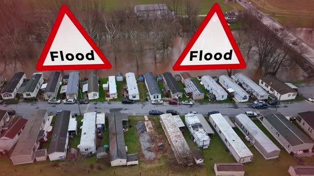 Aerial view of a flooded mobile home park with large Flood signs animated. Aerial truck shot above low income housing on riverbed. Caution signs, flood, natural disaster theme. Special effects drone.