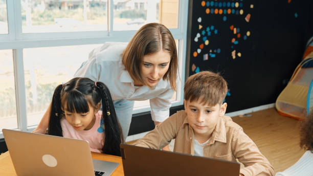 istock African girl play laptop with multicultural friend learning prompt. Erudition. 2149148806