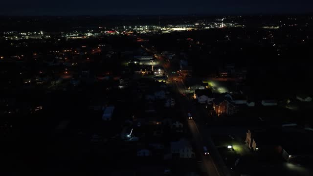 American town at night. High aerial view of traffic and lights of downtown in distance.