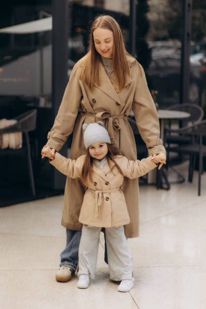 istock mother and daughter walk through the spring city dressed in coats 2149148844