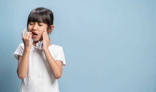 istock The girl is eating chocolate candy and has a toothache. 2149149715