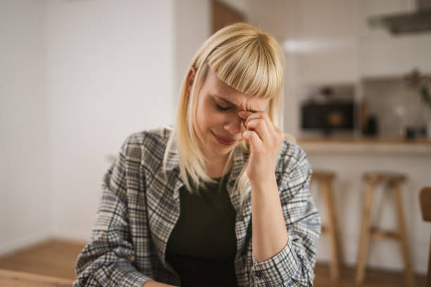 istock Young exhausted woman has eyestrain while browse internet at kitchen at home 2149150320