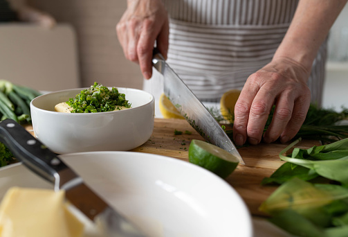 Making herb butter by woman´s hands in the kitchen on a cutting board with fresh ingredients.