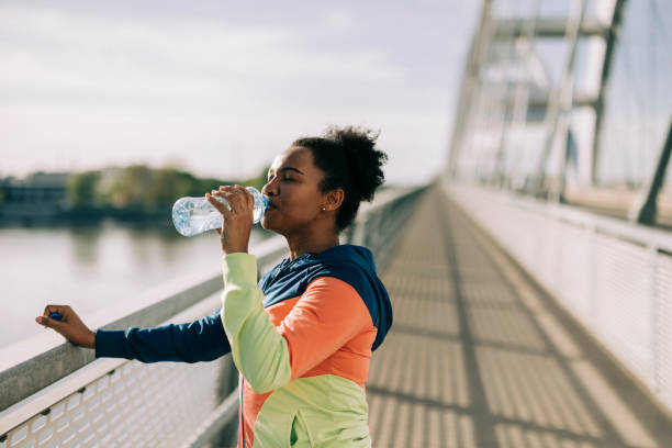 istock Mid adult female runner drinking water after jogging 2149153518