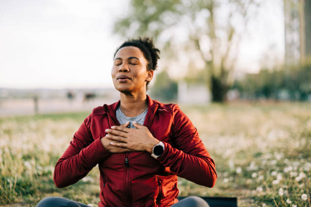 Black woman, breath and hand on chest, for meditation and wellness being peaceful to relax. Bokeh, African American female and lady outdoor, in nature and being calm for breathing exercise and health Black woman, breath and hand on chest, for meditation and wellness being peaceful to relax. Bokeh, African American female and lady outdoor, in nature and being calm for breathing exercise and health breath vapor stock pictures, royalty-free photos & images