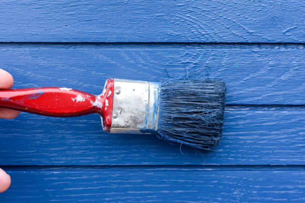 istock Paint brush painting blue paint onto a wooden surface 2149155556