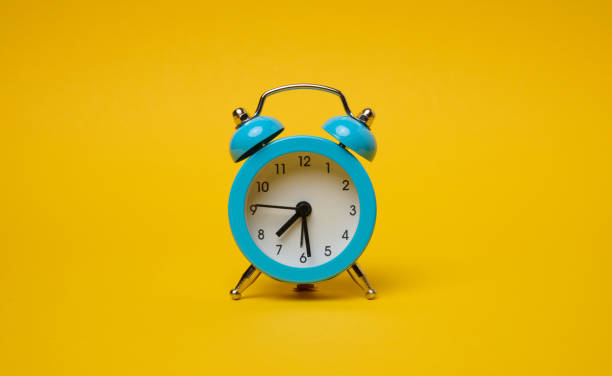 istock Round alarm clock on a yellow background, half past seven in the morning. 2149156159
