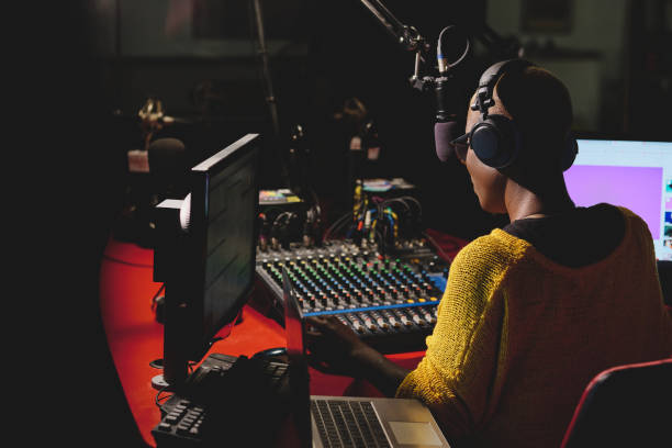 istock Black radio host in headphones working in dark studio 2149156548