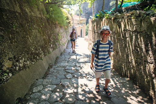 Two kids hiking in Amalfi coast, Campania, Italy. Little boy and teenage girl are walking on a trail through the lemon orchards in the mountains.\nShot with Nikon D850