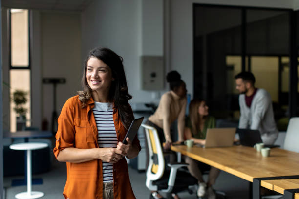 istock Beautiful smiled businesswoman standing inside modern office and looking at digital tablet 2149162110