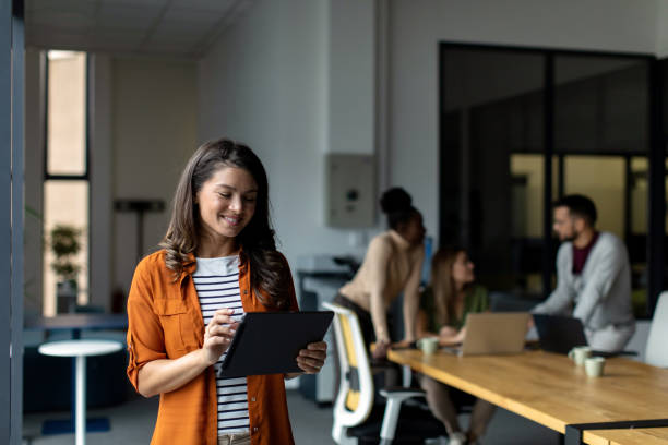 istock Beautiful smiled businesswoman standing inside modern office and looking at digital tablet 2149162361