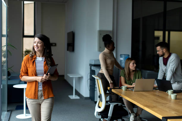 istock Beautiful smiled businesswoman standing inside modern office and looking at digital tablet 2149162362