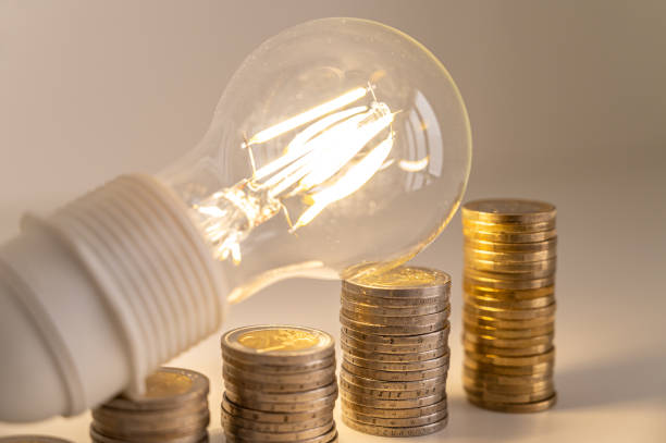 istock Light bulb, above stacks of coins. Electricity costs. 2149162960