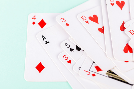 Selection of playing cards in disarray against a soft green background. Leisure games, entertainment and pastime activities abstract concept symbol, nobody. Casual play, game theory, winning losing