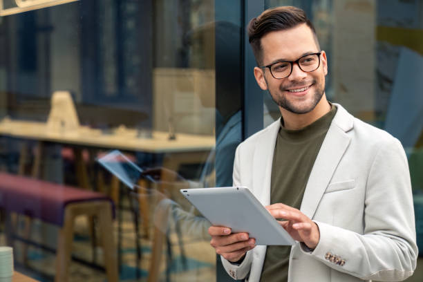 istock Young businessman in suit holding digital tablet looking aside 2149163593