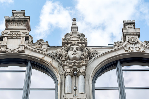 Closeup view of the architectural details on Polish Wroclaw historic Post Office building, showcasing sculptural elements and intricate stonework against a cloudy sky