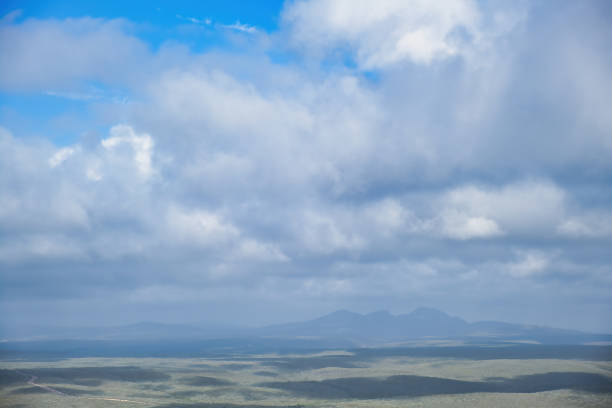 Vast, abstract landscape with hills in soft grey-green color tones, misty mountains in the background and beautiful cloudscape. Fitzgerald River National Park, Western Australia, as seen from Mount Barren