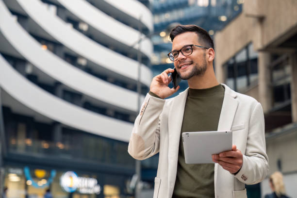 istock Business man talking on cell phone looking away holding digital tablet 2149163843