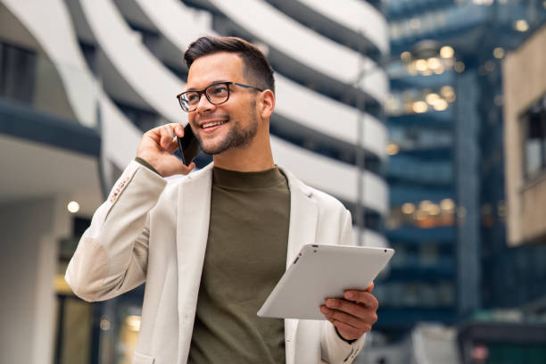 istock Business man talking on cell phone looking away holding digital tablet 2149163896