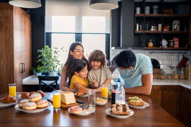 istock Small cute kids with two parents sitting at kitchen table enjoying breakfast at home in the morning 2149165008