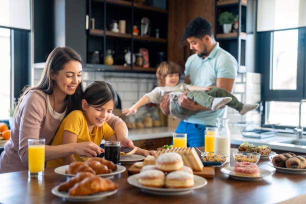 istock Young girl with her mom preparing breakfast while dad is playing with son 2149165780