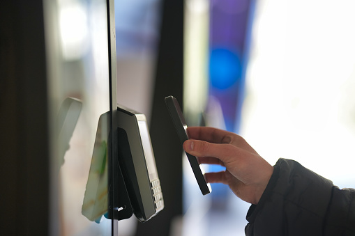Hand using a mobile phone to complete a contactless transaction at a store.