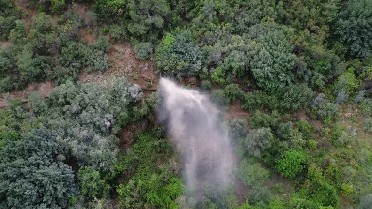 Drone footage shows emergency, pressure burst in mountain pipe. View of emergency, pressure causing water spray in canyon. Aerial capture of emergency, pressure in natural setting