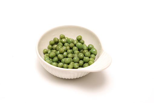 Green peas in a bowl isolated on a white background.