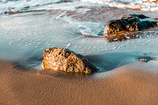 sea, waves, beach, sand and stone at sunset time.
