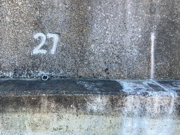 istock Number 27 painted in white paint on to a Beach Concrete protective wall - to show here an allocated beach hut is to be located 2149169578