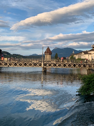 Long wooden Bridge in Lucerne Swizerland with yellow clouds and reflection in water