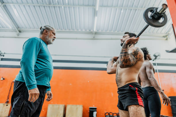 istock Fitness instructor helping student with weightlifting at gym 2149170090