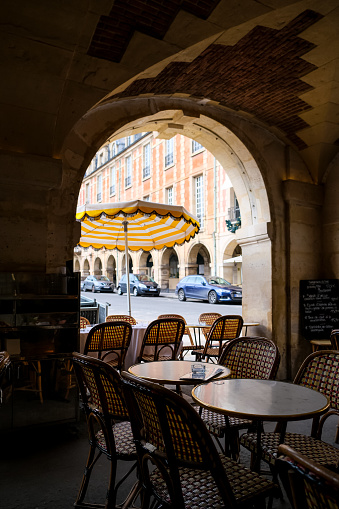 Paris, France - 20.02.2024. View of Cafe Hugo at Place des Vosges in Paris. Charming view from vaulted arcade. Spring in Paris. Popular touristic Brasserie.