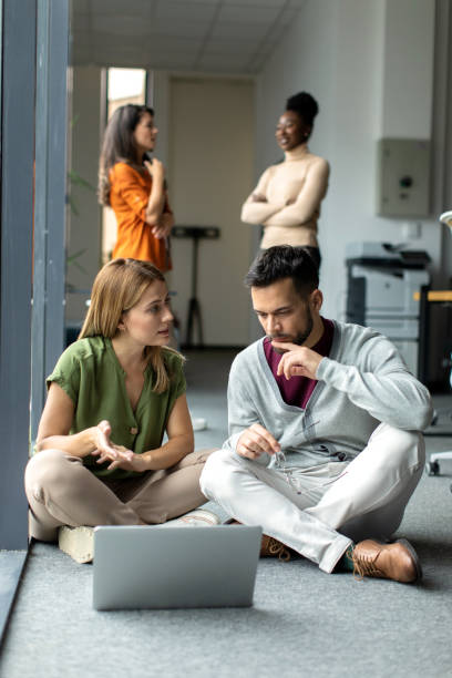 istock Business colleagues sitting on the ground and working on a laptop inside modern office 2149170910