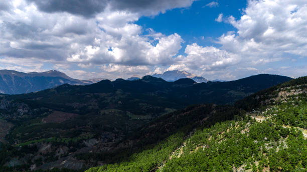 Cloudy, sunny clear weather. The sun is in the clouds. Mountainous area valley view. Mountains with snowy peaks. The valley is in shadow. Mediterranean region. Mountain range view