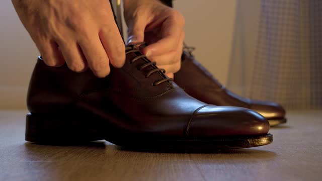 Close-up of a man tying his black leather wedding shoes