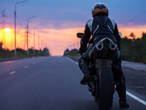 istock motorcyclist stands on an empty road at sunset , back view , copy space. Travel concept 2149174437