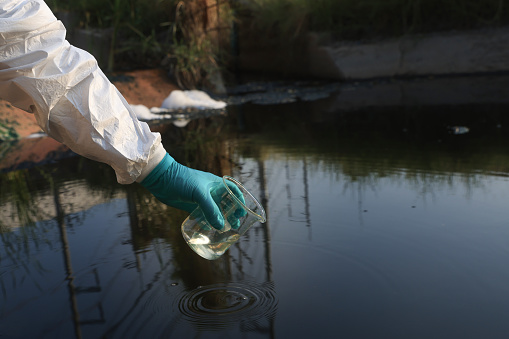 Scientists or Environmental staff collect samples of wastewater from factories, Pollution of ecology and environment concept