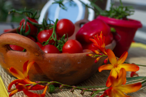 Some fresh red cherry tomatoes in old pottery with some bright orange flowers
