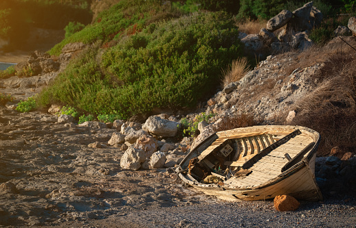 An old wooden boat lies on the seashore.