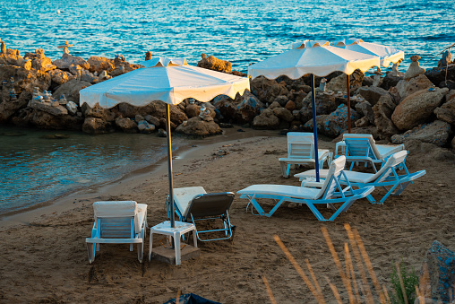Cozy little sandy beach with sun loungers at sunset.