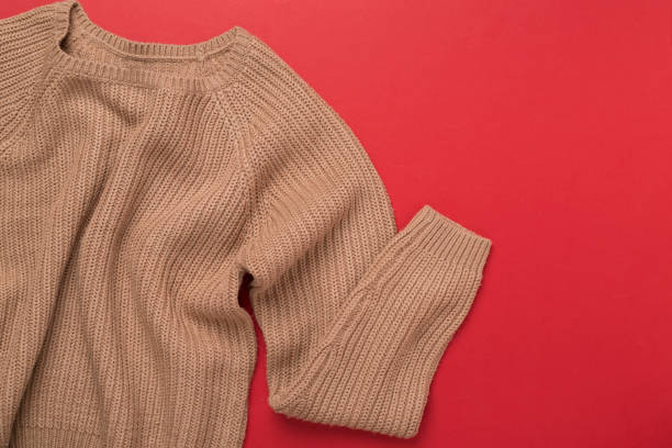 istock Beige knitted sweater on color background, top view 2149177585
