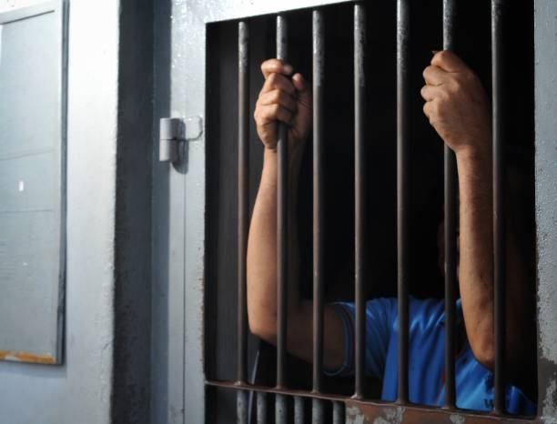 istock hands of a prisoner behind prison bars 2149178121